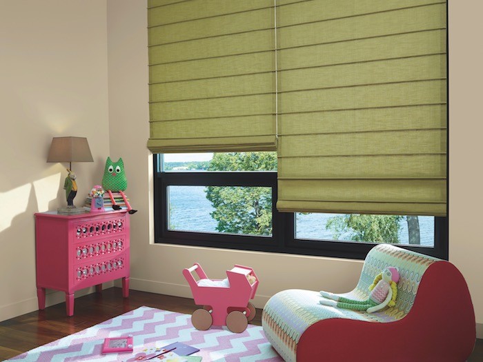 A girl's room with muted lime green shades and pink furniture.